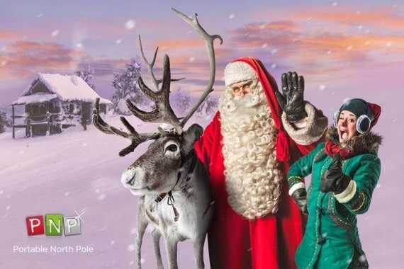 Santa Claus and a young girl with reindeer in a snowy landscape during Christmas.