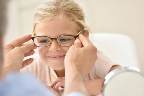 Child getting fitted for glasses by an optometrist.