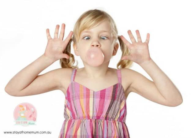 Child blowing bubble gum with playful expression.