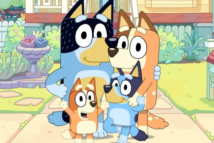 Dog family with two adult dogs and two puppies in a colourful garden.