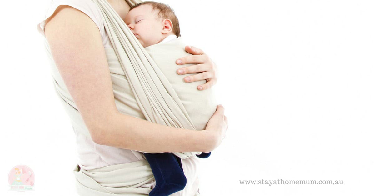 Woman carrying a baby in a beige fabric sling, close-up of the sling's fabric and support.