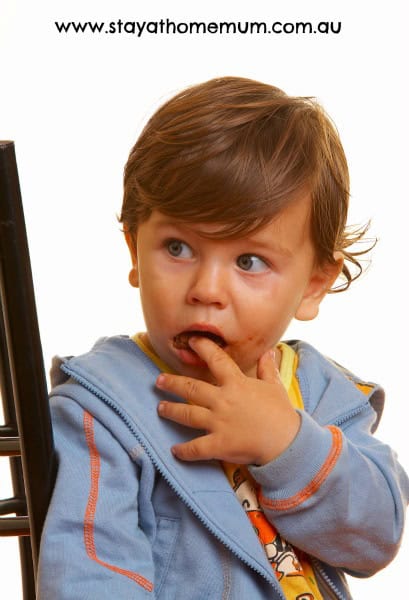 Child with curious expression touching mouth, illustrating children swallowing the darndest things.