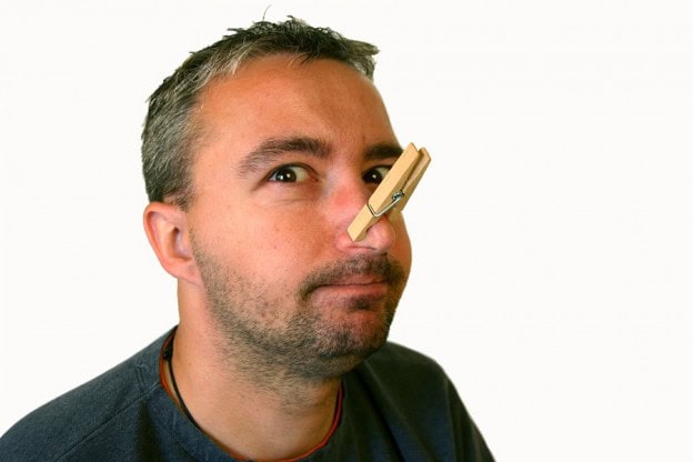 Squeamish person with clothespin on nose, avoiding unpleasant smells or sights.