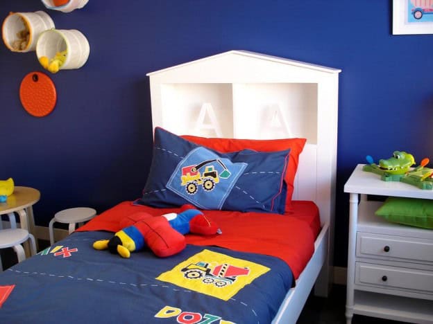 Bright kids' bed with colourful doona and pillows featuring toy truck designs.