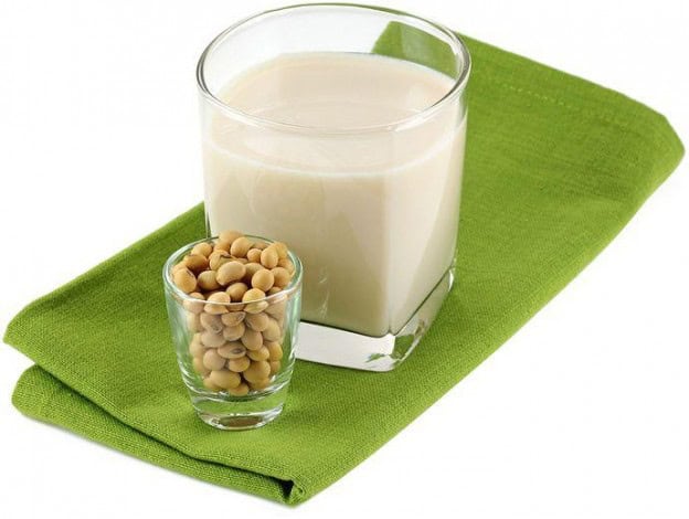 Dairy-free soy milk in a glass with soybeans on a green cloth. Perfect for dairy-free cooking and re.