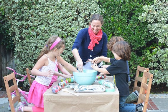 Kids and mother making DIY crafts together outdoors.