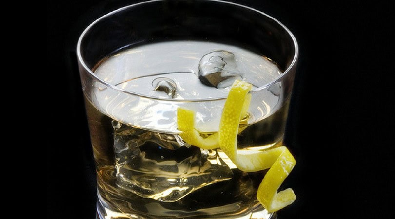 Classic Rusty Nail cocktail with whiskey and Drambuie garnished with lemon peel.