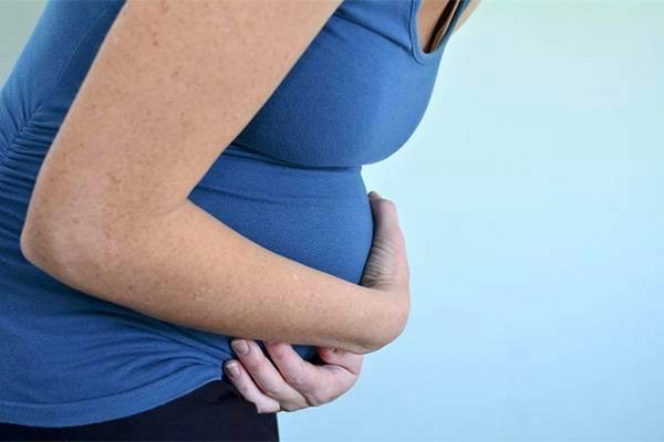 Pregnant woman with hand on her belly, highlighting placental issues during pregnancy.
