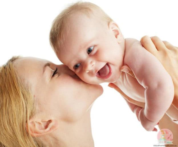 Mother and baby bonding, close-up of a mother kissing her smiling infant.