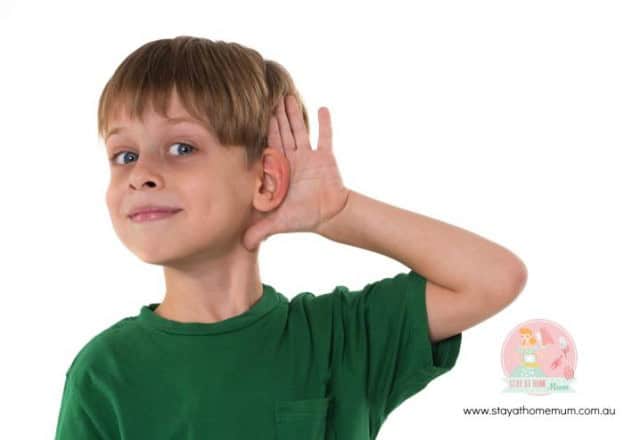 Child with auditory processing disorder holding hand to ear, raising awareness.