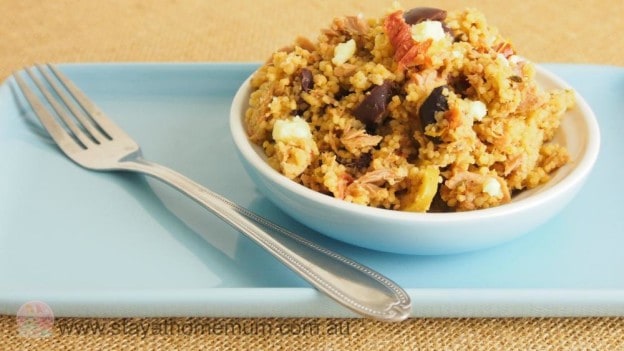 Antipasto couscous with olives, cheese, and vegetables in a white bowl.