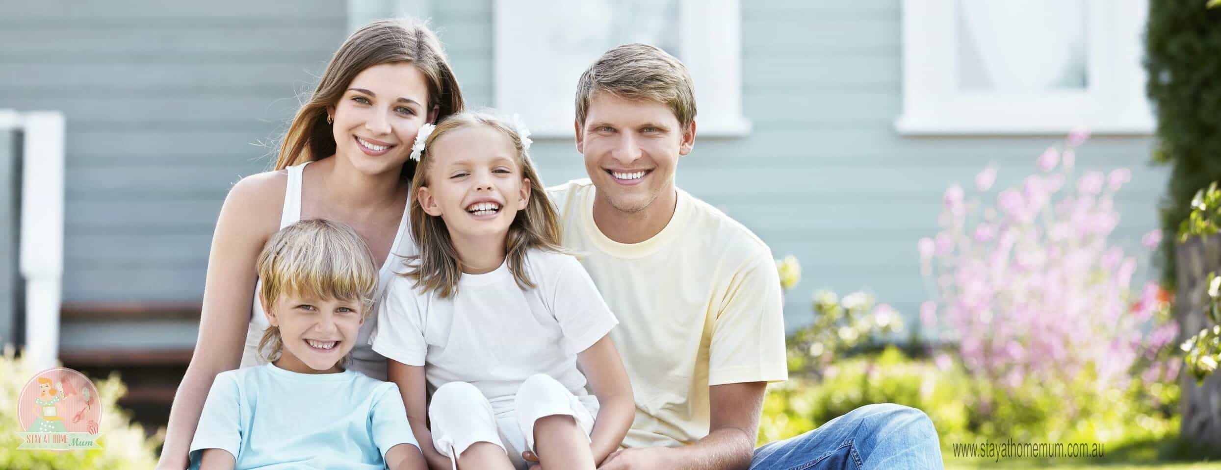 Family outdoor portrait with smiling parents and children in a garden setting.