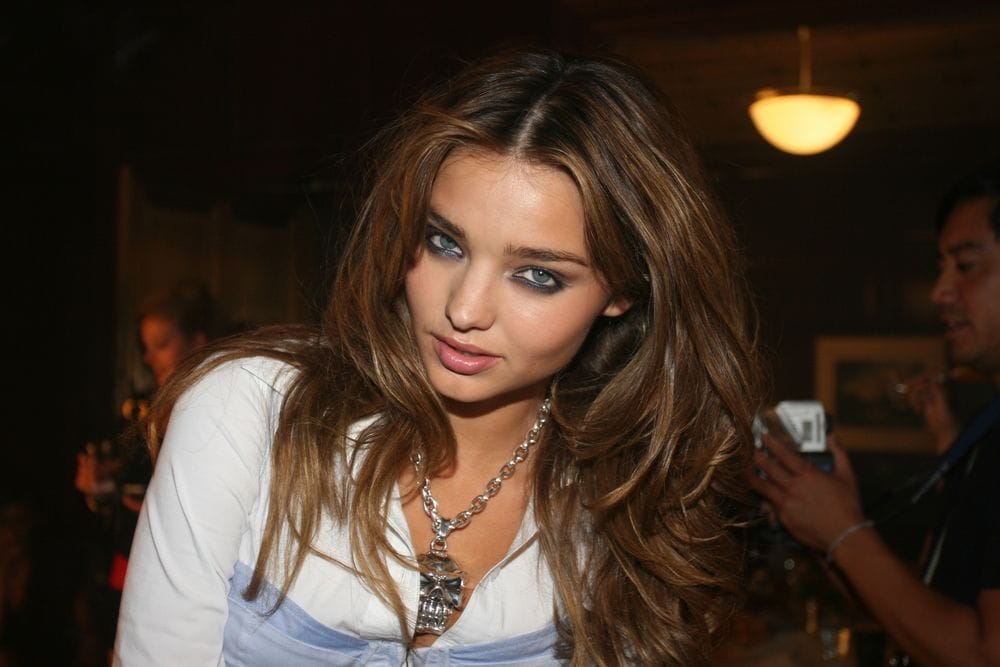 Stylish woman with denim outfit and wavy hair at a social event.