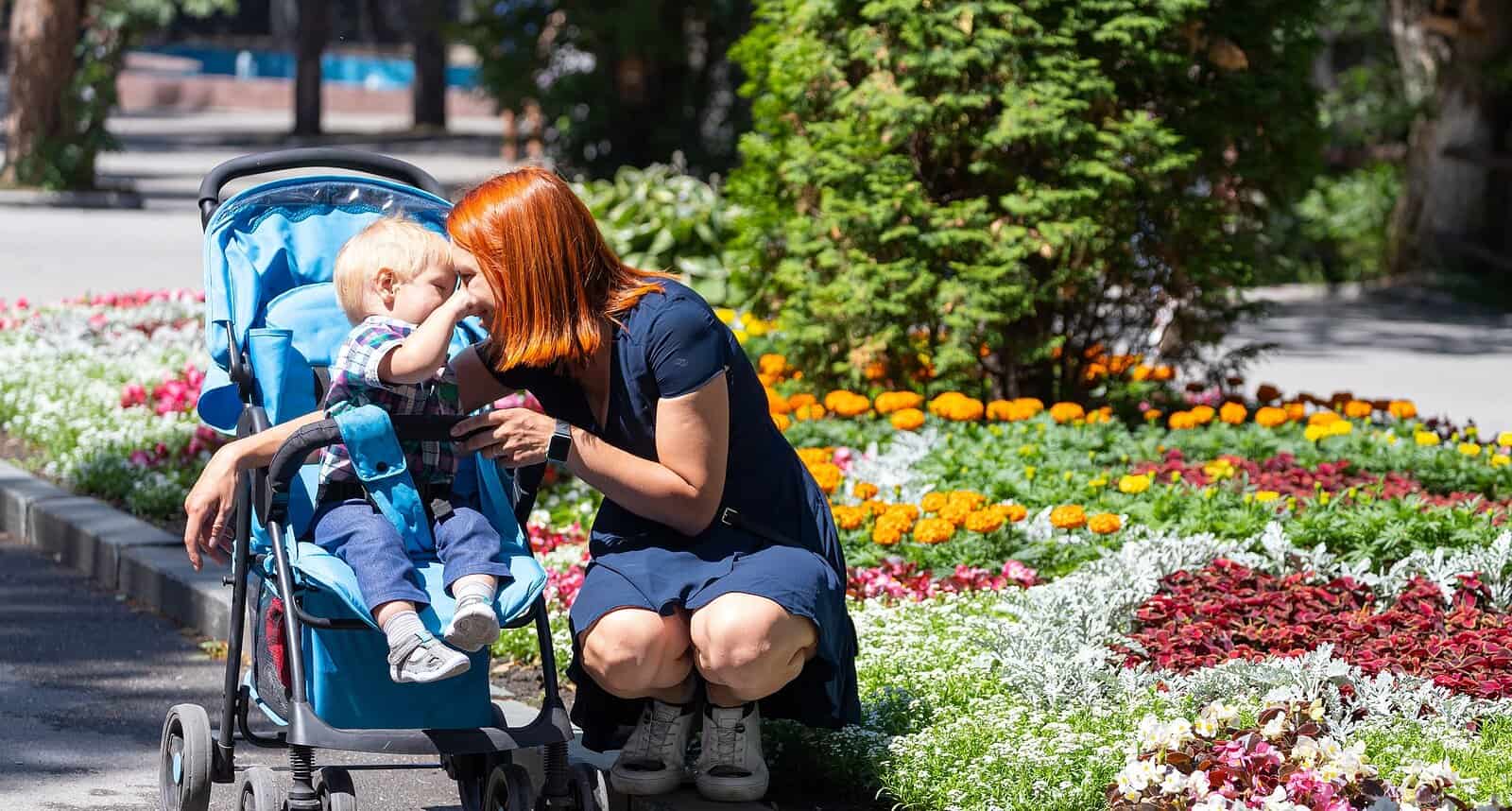 Mother and toddler with stroller enjoying a sunny day outdoors.