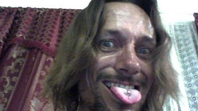 Close-up of a person with long hair and a tongue piercing, smiling with their tongue out.