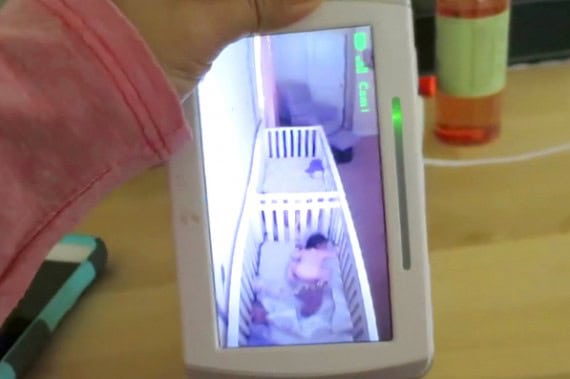 Two babies in a crib appear to be pretending to sleep, captured on a smartphone screen.