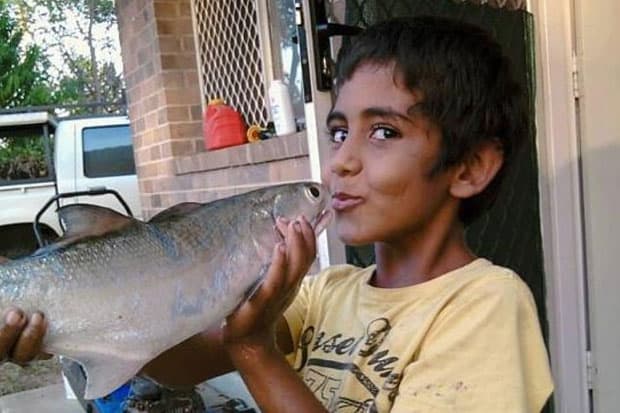 Boy holding a big fish he caught, smiling proudly outdoors in Australia.