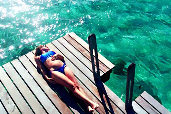Woman sunbathing on a dock near the water, enjoying a peaceful moment outdoors.