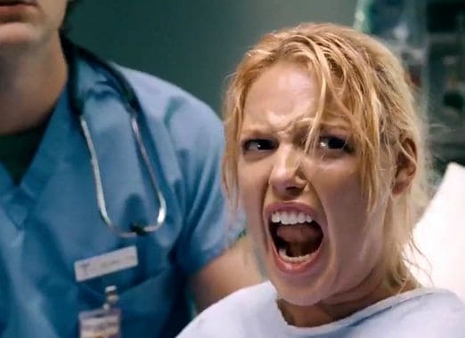 Woman in labor showing discomfort and pain in a hospital setting.