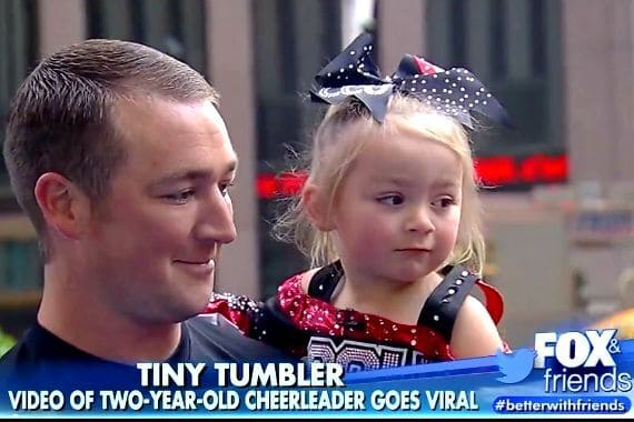 Adorable two-year-old cheerleader in costume during a cheerleading routine.