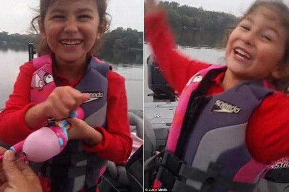 Girl smiling and giggling after catching a large fish on a boat.