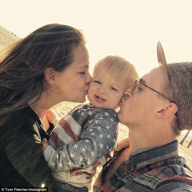Happy family sharing kisses with their young child.