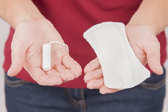Woman holding a tampon and a pad for feminine hygiene comparison.
