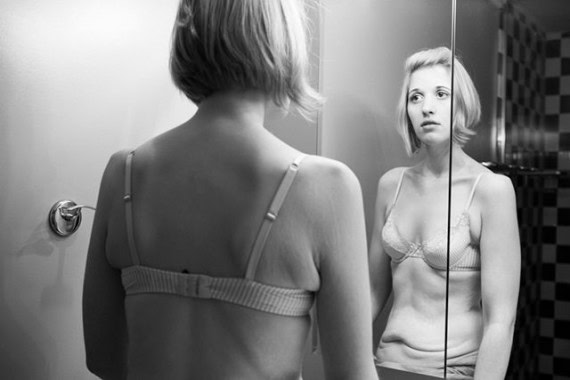 Empowering woman reflecting on her weight loss journey in front of a mirror.