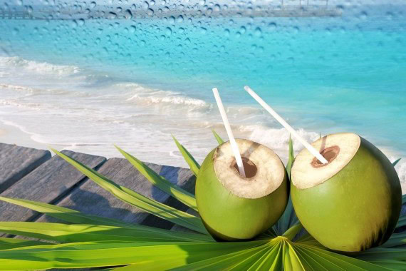 Coconuts with straws on a beach, highlighting hydration and health benefits of coconut water.