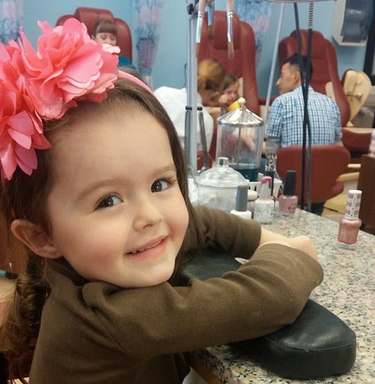 Cute girl at nail salon with pink flower headband.