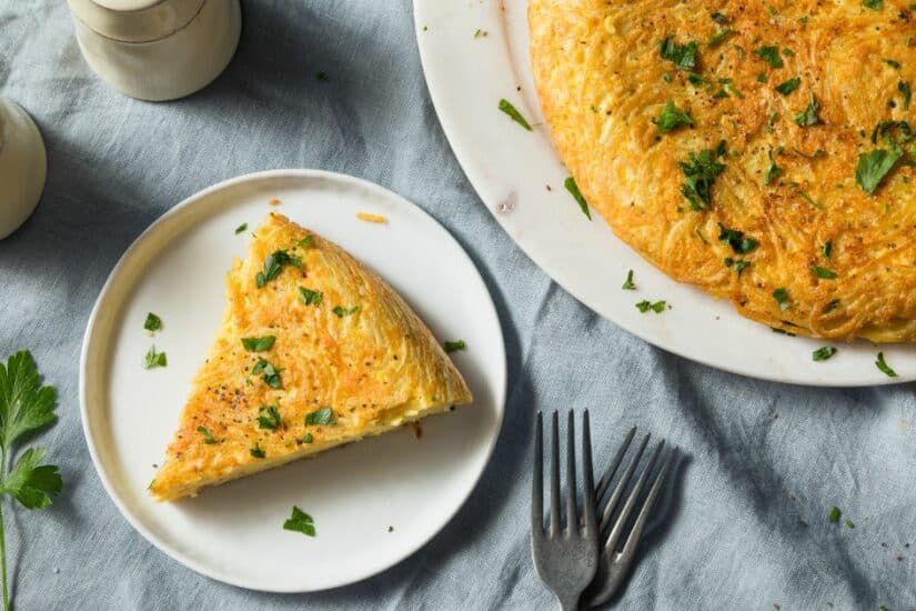 Delicious spaghetti omelette with herbs served on a white plate, perfect for a quick and tasty meal.