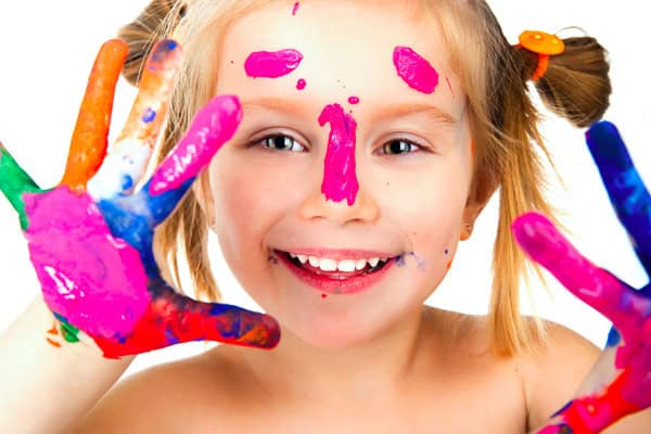 Happy girl with painted hands and face, encouraging creativity in children.