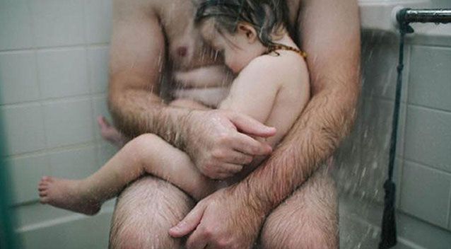 Father cradling his sick son in a warm, caring moment during bath time.