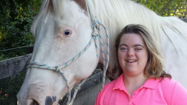 Mum with Down syndrome daughter and white horse outdoors.