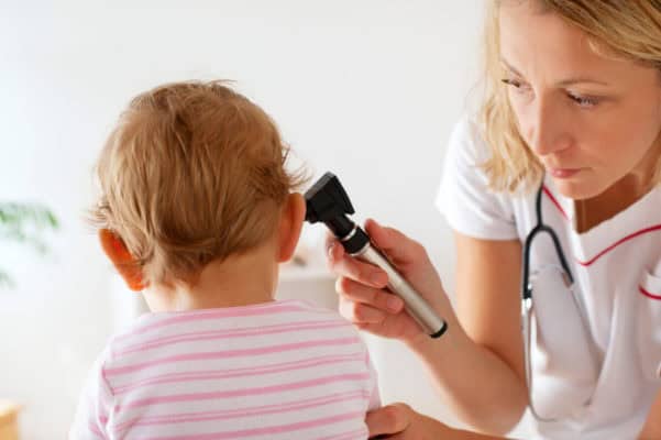 Doctor examining child's ear with otoscope.