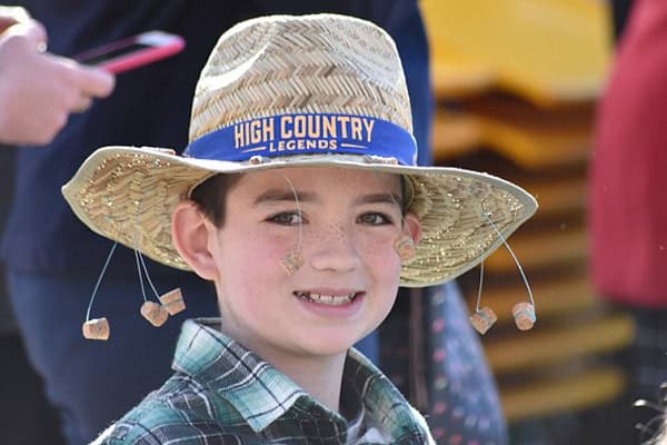 Boy with straw hat at outdoor event.