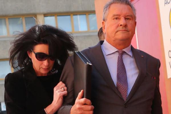 Man and woman walking outdoors, woman holding onto man's arm.