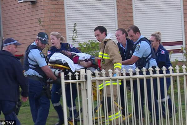 Emergency responders carry a young girl on a stretcher from a house fire scene in Sydney.