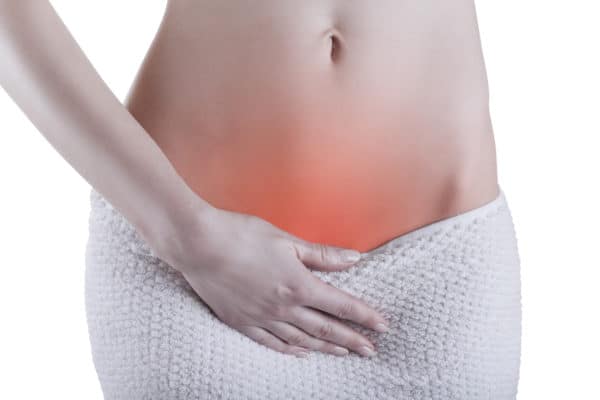 Woman holding lower abdomen indicating discomfort or confusion with vaginal health.
