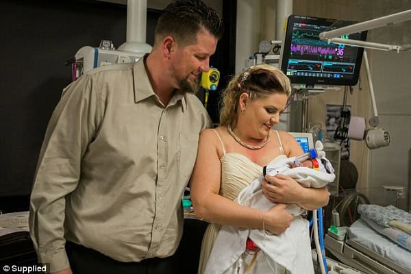 Couple holding their premature baby in neonatal intensive care unit.