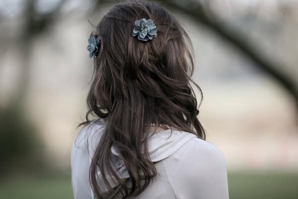Young girl with floral hair accessories looking away in a park setting.