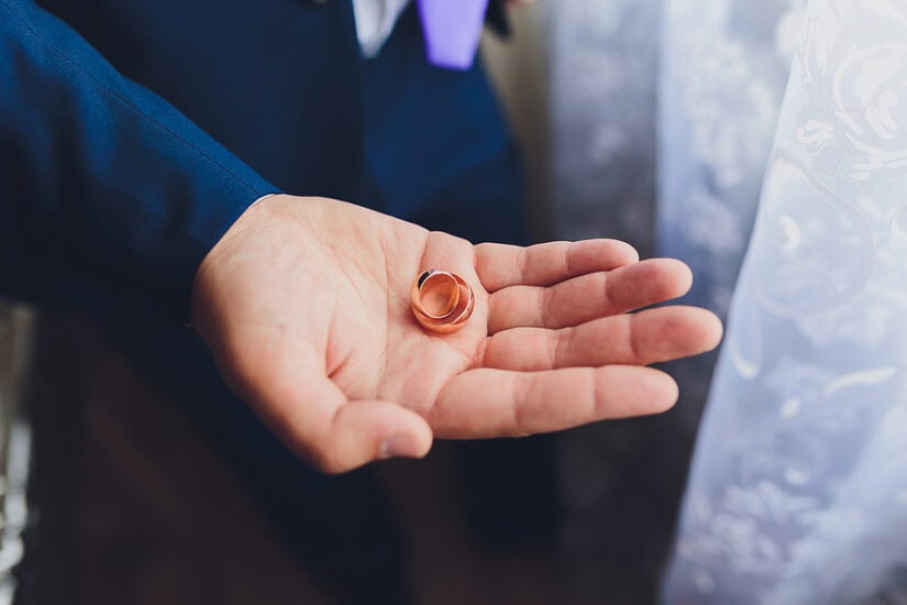 Men's wedding ring displayed in hand, symbolising commitment.
