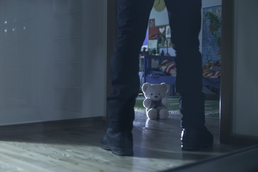 Child's teddy bear hidden behind a door in a child's bedroom.