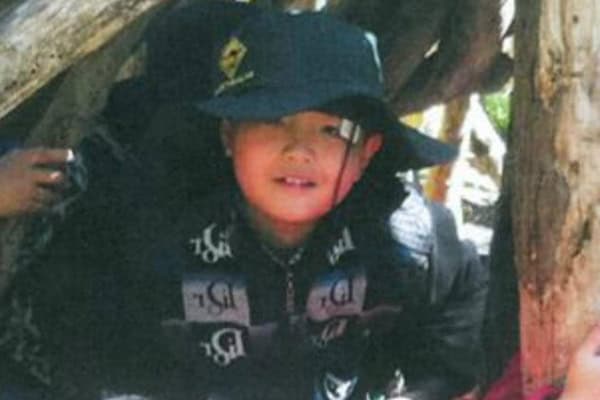 Child in wide-brimmed hat during outdoor school excursion.