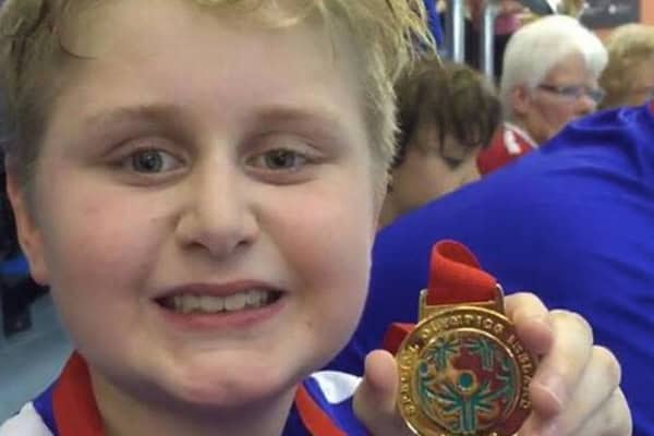 Young boy holding a medal after a swimming competition.