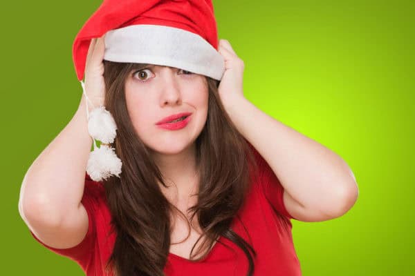 Woman in Santa hat looking stressed, holiday chaos, Christmas anxiety relief.
