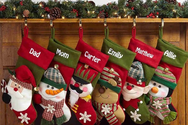 Festive Christmas stockings personalized with family member names hanging on a wooden mantel.