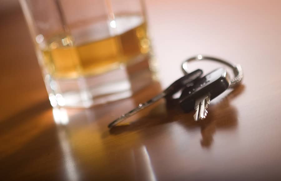 Glass of alcohol and keys on table, related to mum caught drink driving with children.