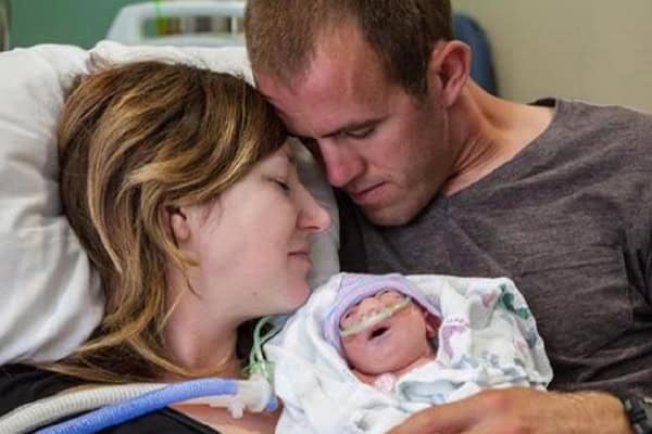 Mother and father share tender moment with their newborn in hospital.