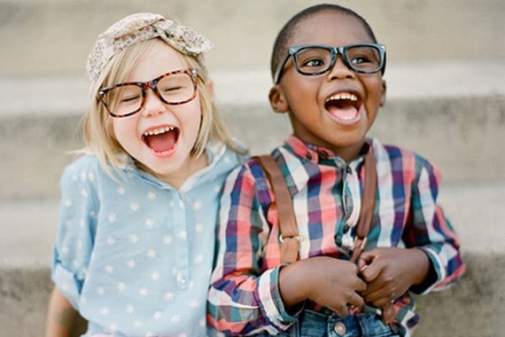 Children laughing and smiling while using devices outside.